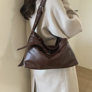 Detail view of large dark brown leather tote bag with wide adjustable shoulder strap