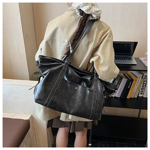 Detail of vintage black leather tote bag with adjustable strap and metal hardware