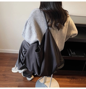 Detailed view of black canvas hobo bag on a model showing large capacity and minimal style