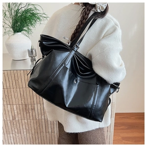Detail view of large black glossy leather tote bag with adjustable shoulder strap and buckle