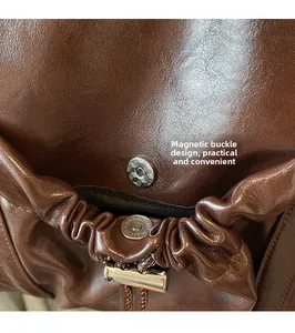 Detail of magnetic snap closure on brown pleated tote bag with oily leather finish