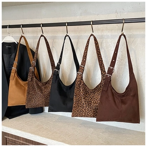 Detail view showing five suede bucket bags in solid colors and leopard prints on a display rack
