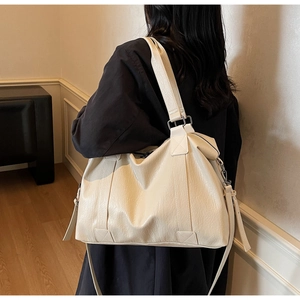 Detail of soft cream PU leather texture and silver hardware on a large tote bag