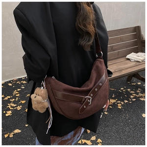 Brown suede crescent bag worn by model in an autumn park with ginkgo leaves