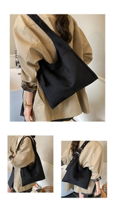 Close-up of black canvas tote bag showing adjustable wide shoulder strap and side pocket