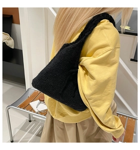 Close-up of black knitted shoulder bag texture styled with a yellow sweatshirt