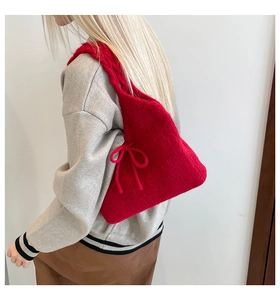 Detail of red knit shoulder bag featuring chunky weave texture and side bow drawstring