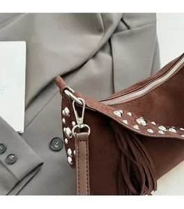 Detail of silver rivets and suede fringe on dark brown bohemian shoulder bag