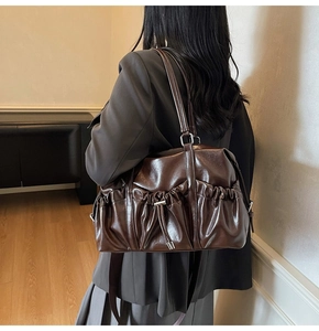Sac cabas en cuir marron avec détails plissés et cordon sur un mannequin en intérieur