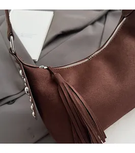 Detail of brown suede crescent bag featuring silver studs and a long leather fringe tassel