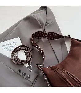 Detail of wide strap with silver studs on dark brown suede tote bag with fringe