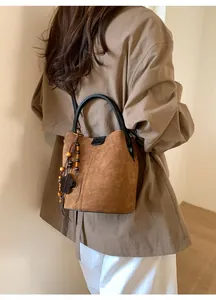 Detail of vintage brown suede bucket bag with wooden bead fringe and black round handles