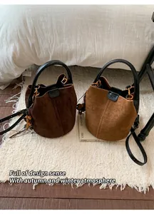 Detail of suede bucket bags with leather handles and ethnic beaded charms on a rug
