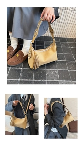 Detail of vintage suede crossbody bag with long tassels and studded wide shoulder strap