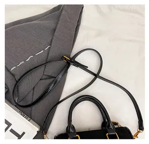 Macro view of the black faux suede bag showing soft shoulder strap and gold metal hardware