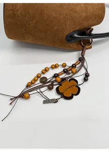 Detail of retro matte brown handbag with ethnic charm featuring wooden beads and metal tag