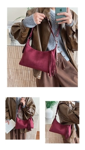 Detail of burgundy suede hobo bag featuring decorative long tassels and silver hardware