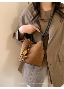 Nahaufnahme der hellbraunen Wildleder-Beuteltasche mit Holzperlen und Blumenquasten-Anhänger