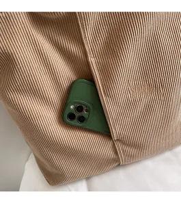 Detail of dark camel corduroy tote with a front pocket for smartphone storage