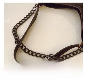 Close-up of a deep brown tote bag featuring a leather strap and bronze chain details