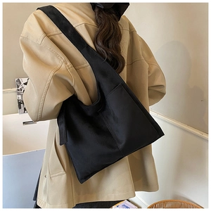 Close-up of minimalist black canvas tote bag with wide strap shown in lifestyle setting