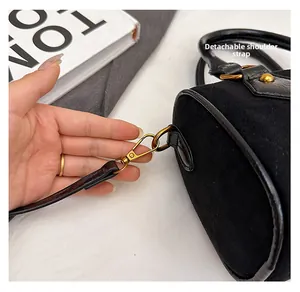 Detail of detachable shoulder strap with golden metal hardware on black suede bag