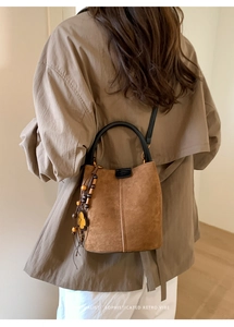 Close-up of retro brown suede bucket bag featuring wooden bead and flower charm details