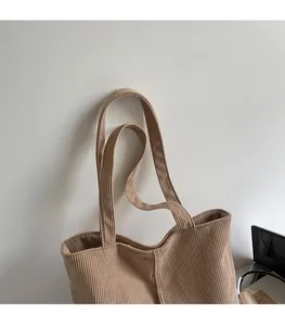Detailed view of wide corduroy straps on a brown tote bag with striped texture