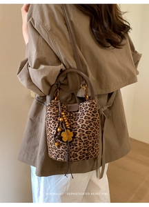 Close-up of leopard print bucket bag with brown leather strap and floral bead charm