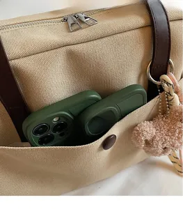 Detail of canvas tote bag showing side pocket for phone and plush bear keychain