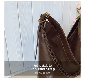 Detail of adjustable strap and gold-tone chain on brown leather bucket bag
