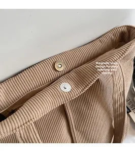 Detail of the magnetic buckle closure and inner zipper pocket on corduroy tote bag