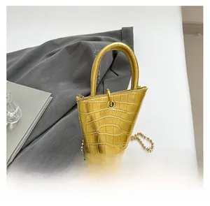Detailed view of golden crocodile textured handbag with unique inverted triangle shape