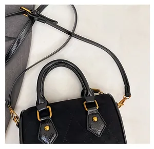 Detailed macro view of black quilted faux suede handbag with gold metal hardware