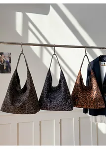 Trois sacs cabas hobo à imprimé léopard en marron, gris et orange sur un support
