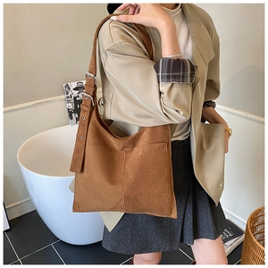 Close-up of brown suede bucket bag featuring front pocket and adjustable buckle strap