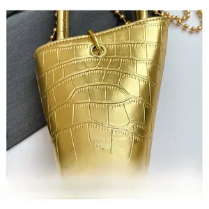 Close-up of metallic gold bucket bag with crocodile texture and fashion metal logo