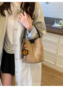 Detail der Vintage-Wildleder-Beuteltasche mit Sonnenblumen-Anhänger und Holzperlen-Quasten