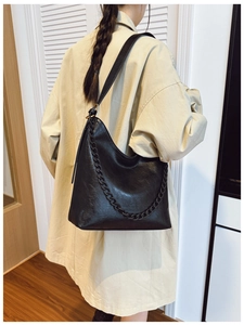 Detail view of the black bucket bag with matte chain strap and textured leather finish