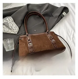 Detail of retro suede brown shoulder bag featuring leather straps and side drawstring