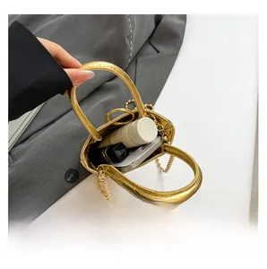 Interior capacity of gold crocodile pattern mini bucket bag showing phone and lipstick