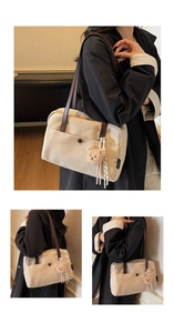 Detail view of a beige canvas tote bag with brown leather handles and a plush bear charm