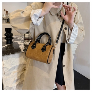 Detail of camel suede Boston bag featuring diamond quilting and black handles