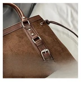 Detail of dark brown suede bag showing fine stitching and silver metal hardware accents