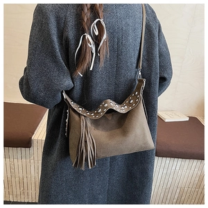 Detail of brown suede shoulder bag featuring vintage silver studs and long tassels