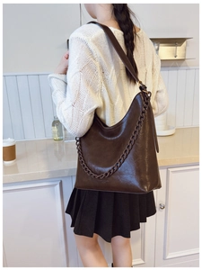 Detailed close-up of brown leather bucket bag with chunky decorative chain strap