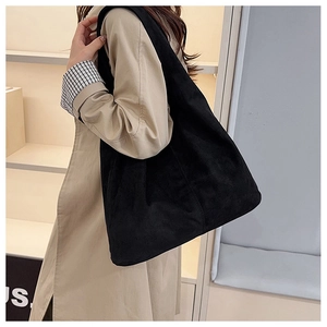 Detailed close-up of a black corduroy tote bag showing textured fabric and hobo style