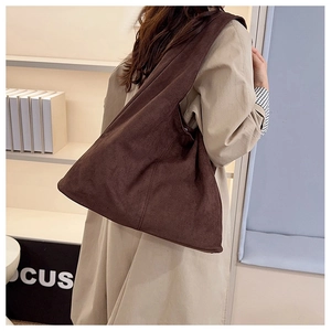 Detail of dark brown suede tote bag featuring a magnetic snap closure and wide strap