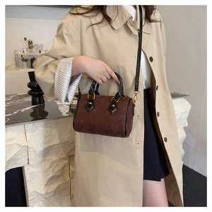 Detalle de bolso acolchado de ante marrón oscuro con costuras y herrajes dorados