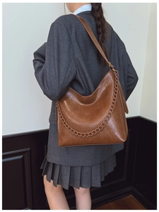Detailed view of the dark brown bucket bag's leather texture and thick decorative chain